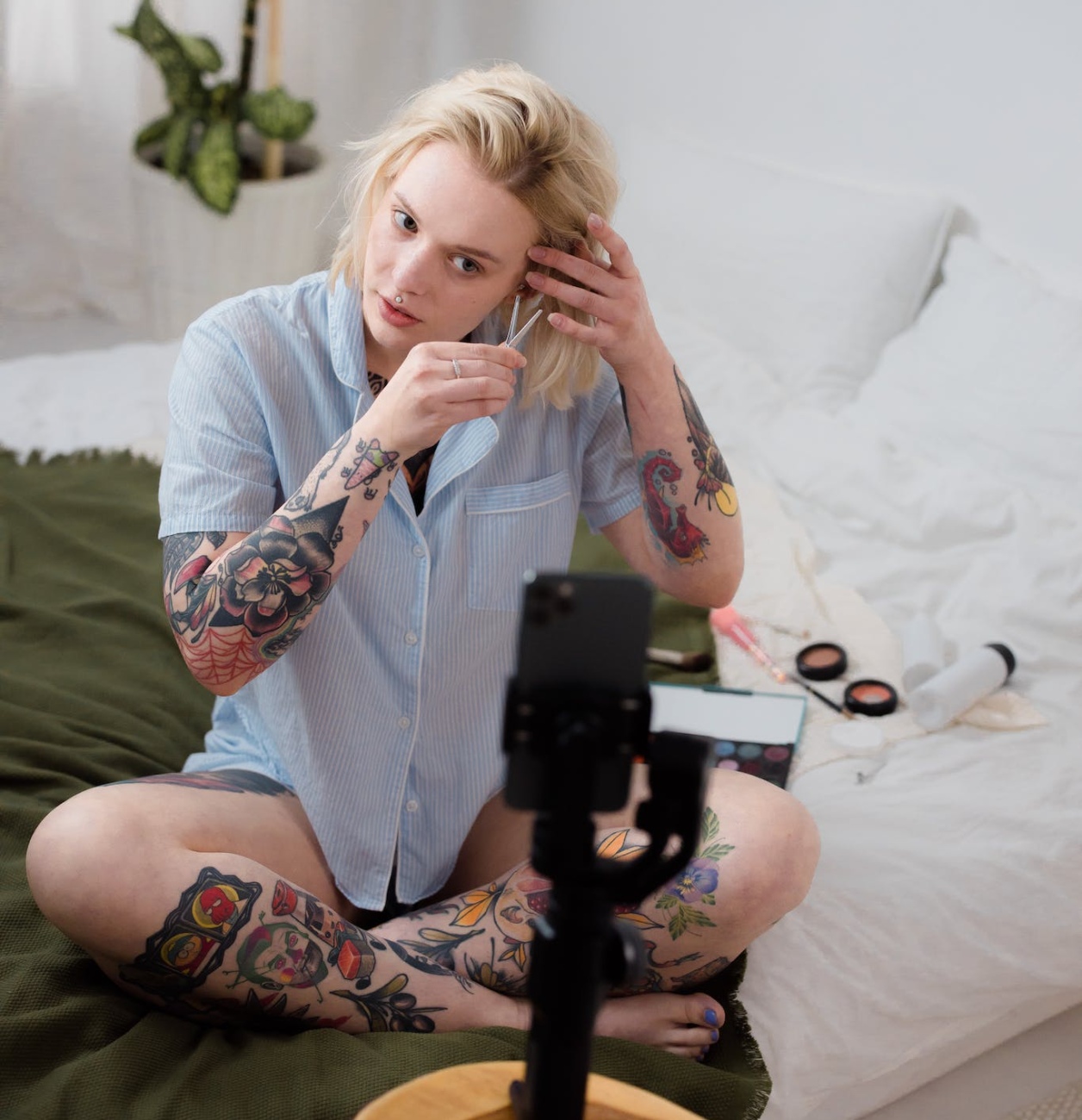 A Tattooed Woman Vlogging on Her Phone while Putting a Clip on Her Hair